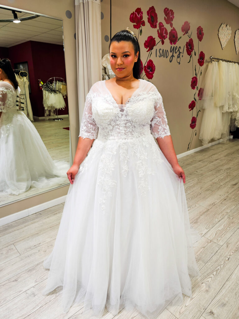 plus size bride wearing floral aline wedding dress with sleeves in whittier california bridal shop